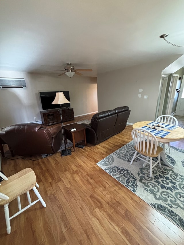 living room featuring an AC wall unit, ceiling fan, and wood-type flooring