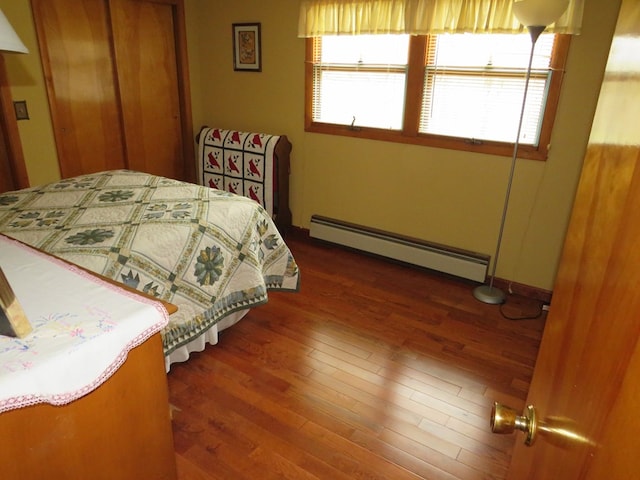 bedroom with dark hardwood / wood-style floors and baseboard heating