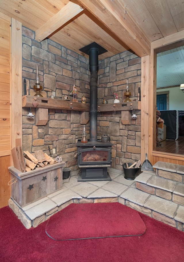 living area with wooden ceiling, beam ceiling, and a wood stove