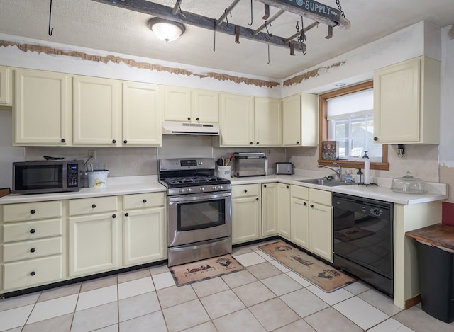 kitchen with stainless steel appliances, cream cabinetry, under cabinet range hood, a sink, and light countertops