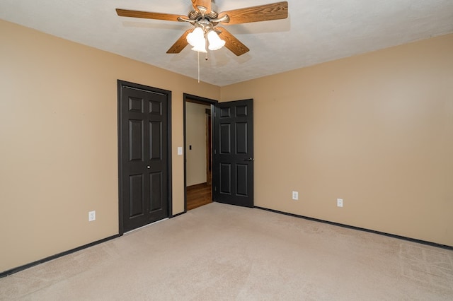 unfurnished bedroom featuring light carpet, baseboards, a ceiling fan, and a closet