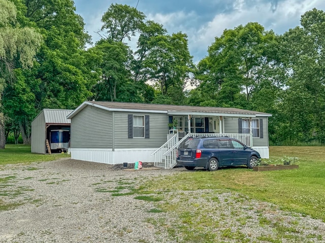 manufactured / mobile home featuring covered porch, driveway, and a front yard