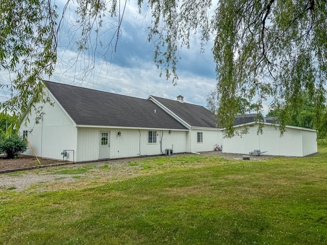 back of property featuring central air condition unit and a lawn