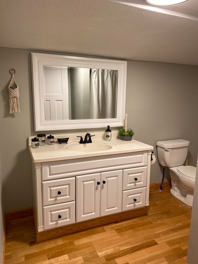 bathroom featuring toilet, a textured ceiling, wood finished floors, and vanity