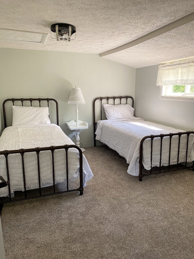 carpeted bedroom with a textured ceiling, beam ceiling, and attic access