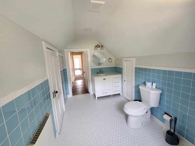 406 E Maple St, Coudersport, PA 16915 - bathroom featuring tile walls, vanity, a wainscoted wall, vaulted ceiling, and tile patterned floors