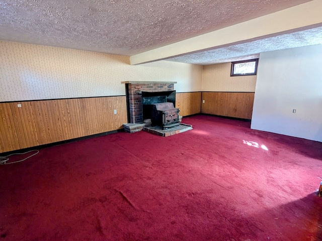 unfurnished living room with a wainscoted wall, a textured ceiling, carpet flooring, and wallpapered walls