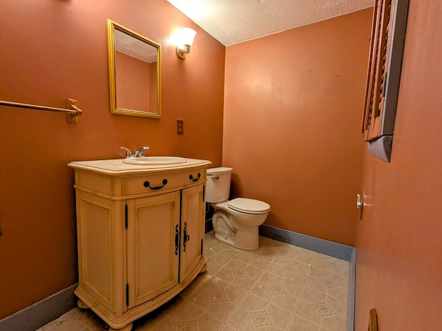 half bath with baseboards, vanity, toilet, and a textured ceiling