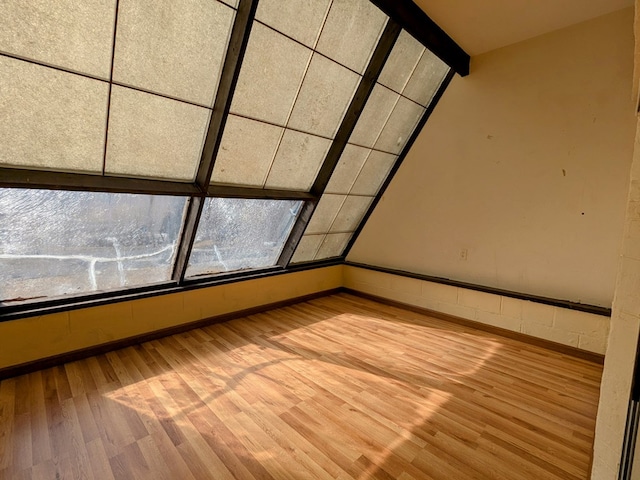 unfurnished room with light wood-style floors, vaulted ceiling with beams, and baseboards