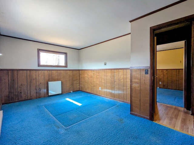 empty room with a wainscoted wall, ornamental molding, and wooden walls