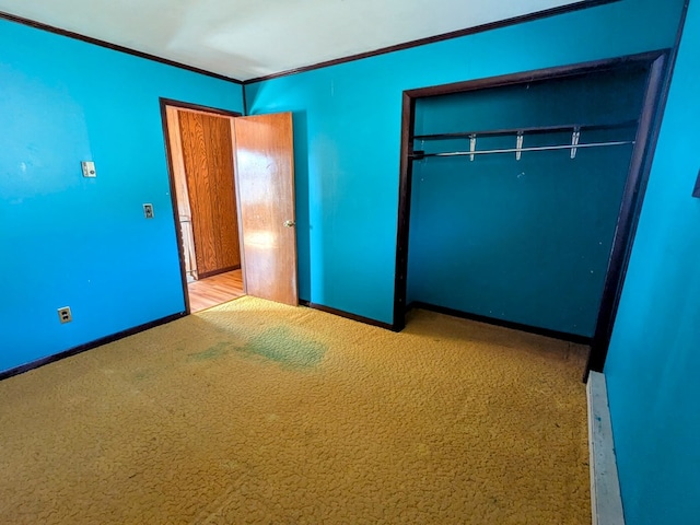 unfurnished bedroom with ornamental molding, a closet, carpet flooring, and baseboards