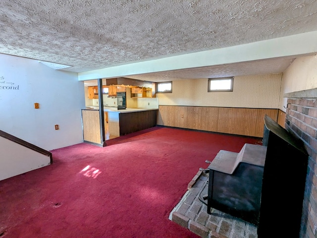 unfurnished living room featuring carpet floors, wainscoting, a textured ceiling, and wooden walls