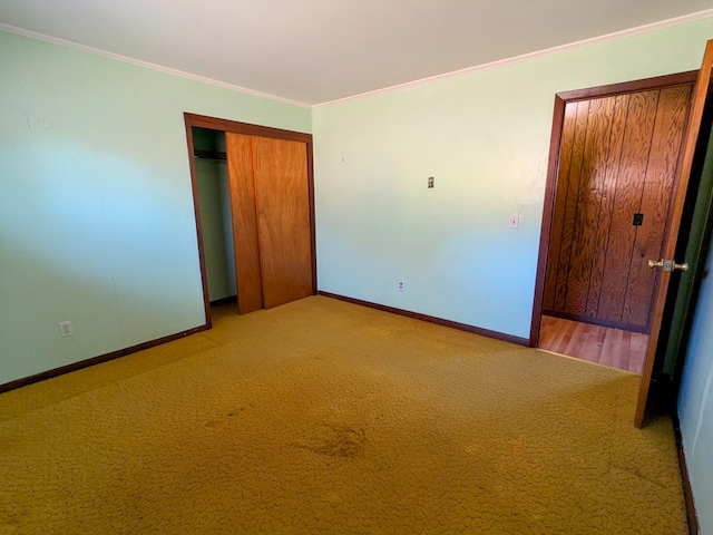 unfurnished bedroom featuring ornamental molding, a closet, light carpet, and baseboards