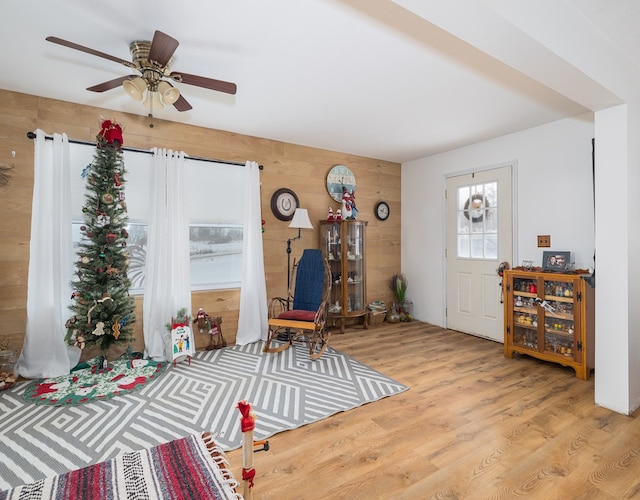 foyer with light hardwood / wood-style floors, ceiling fan, and wood walls