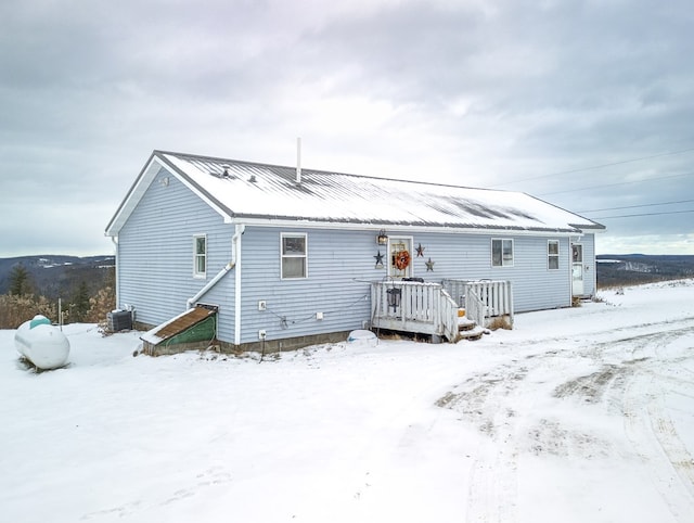 snow covered property featuring cooling unit and a deck with mountain view