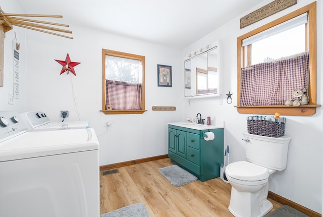 bathroom featuring hardwood / wood-style flooring, plenty of natural light, toilet, and washing machine and clothes dryer