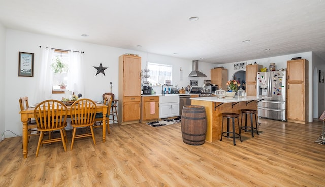 kitchen with stainless steel appliances, a kitchen island, a wealth of natural light, and wall chimney exhaust hood