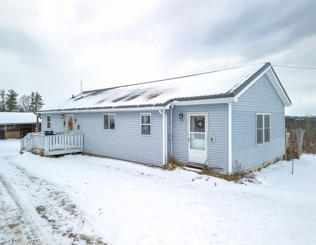 snow covered back of property featuring a deck