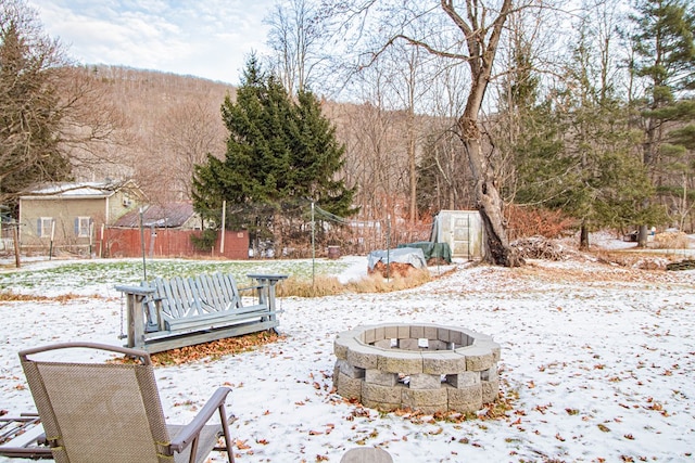 yard covered in snow with an outdoor fire pit