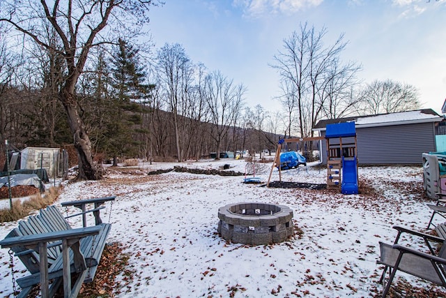 yard layered in snow featuring a playground and a fire pit