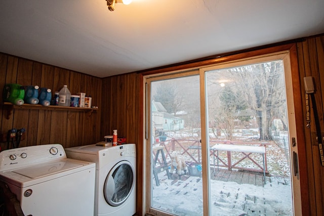 clothes washing area with washing machine and dryer and wood walls