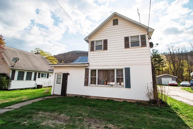 traditional-style home featuring driveway, an outbuilding, a front yard, and metal roof