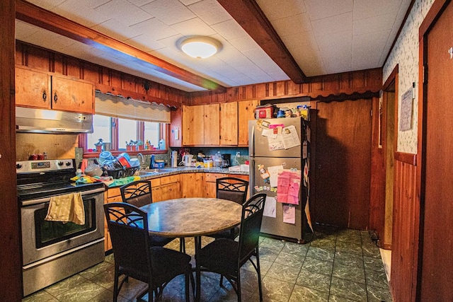 kitchen featuring beam ceiling, sink, stainless steel appliances, and wooden walls