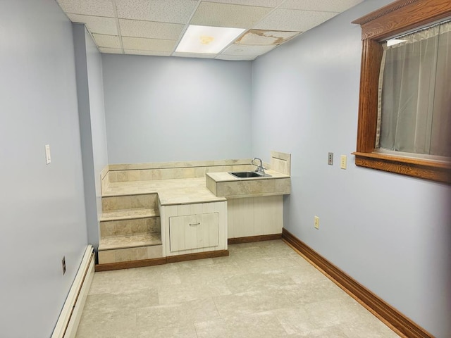 bathroom with a paneled ceiling, baseboard heating, and sink