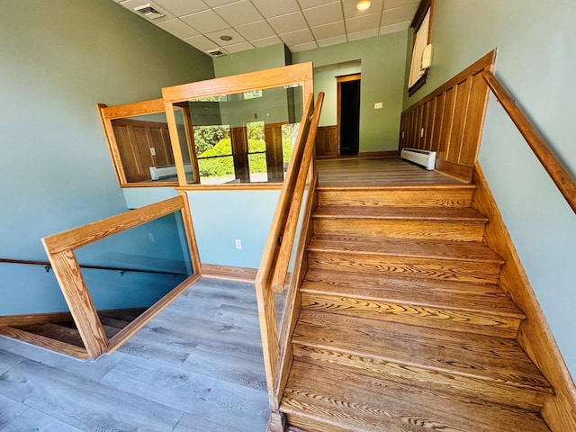 stairs featuring hardwood / wood-style floors, a paneled ceiling, and baseboard heating