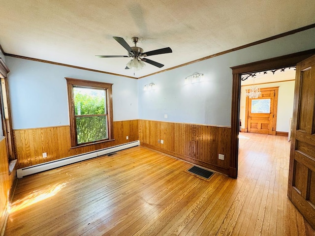 spare room with light wood-type flooring, ornamental molding, a textured ceiling, ceiling fan, and a baseboard radiator