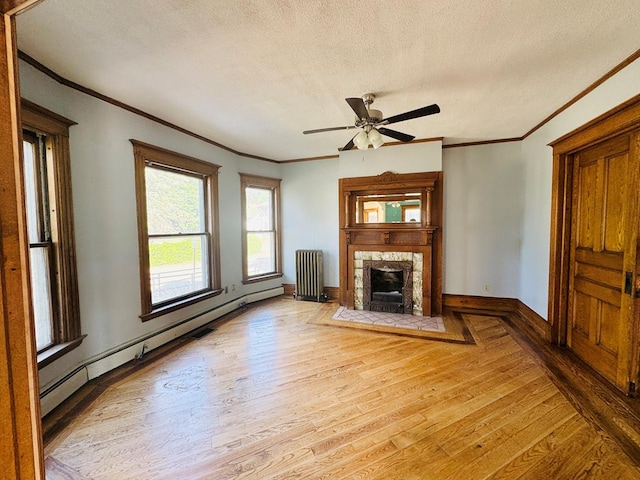 unfurnished living room with ceiling fan, baseboard heating, light hardwood / wood-style floors, radiator heating unit, and a tiled fireplace