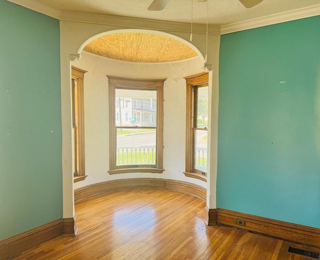 empty room with ceiling fan, crown molding, a textured ceiling, and hardwood / wood-style flooring