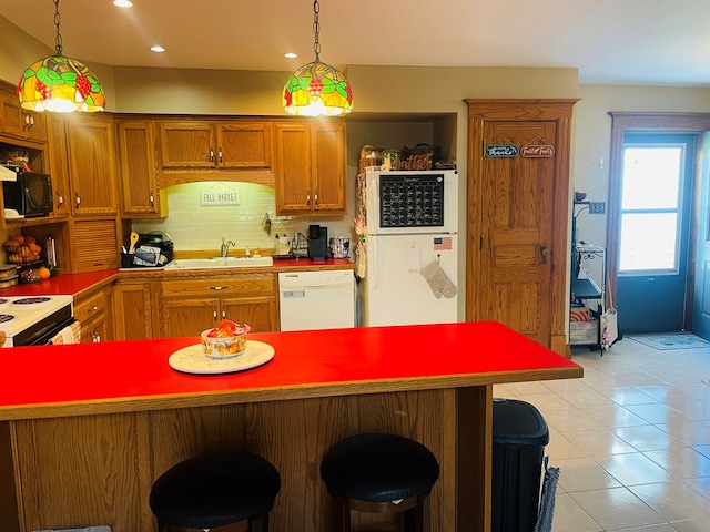 kitchen with backsplash, decorative light fixtures, white appliances, and sink