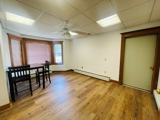 dining room featuring a paneled ceiling, light hardwood / wood-style flooring, and a baseboard radiator