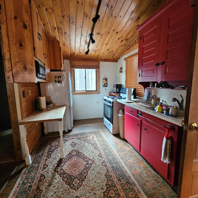 kitchen featuring range with gas stovetop, brick floor, light countertops, wood ceiling, and black microwave