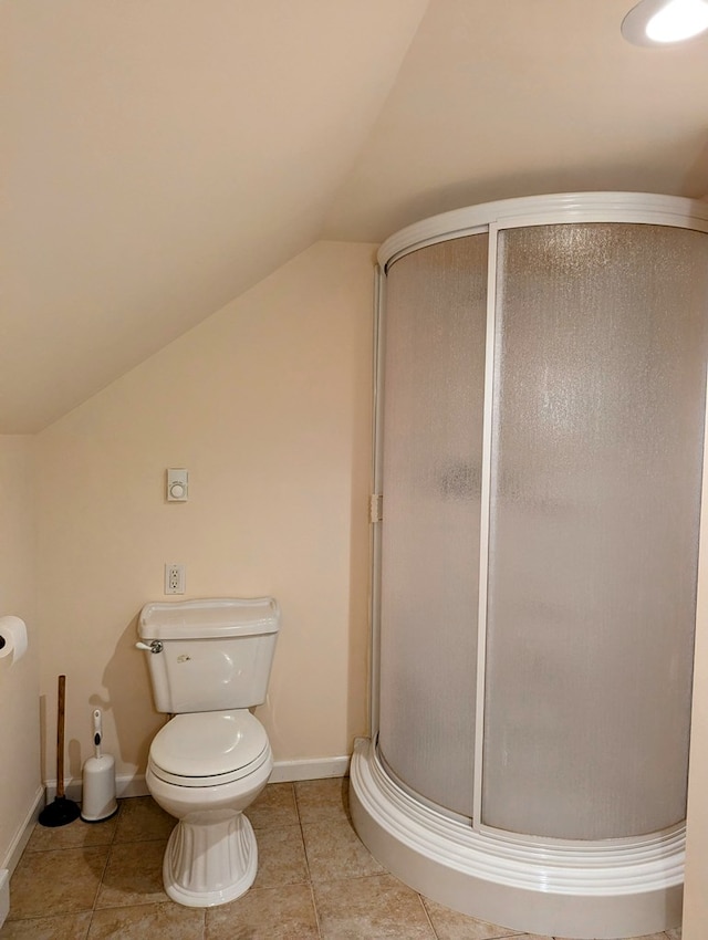 bathroom featuring a shower with door, vaulted ceiling, tile patterned flooring, and toilet