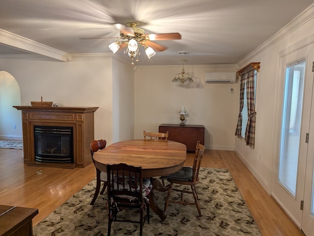 dining area with ceiling fan with notable chandelier, light hardwood / wood-style flooring, a wall unit AC, and crown molding