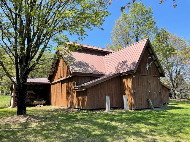 view of side of property with a lawn, metal roof, a barn, and an outbuilding