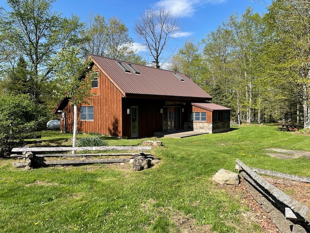 rear view of house featuring a yard and metal roof
