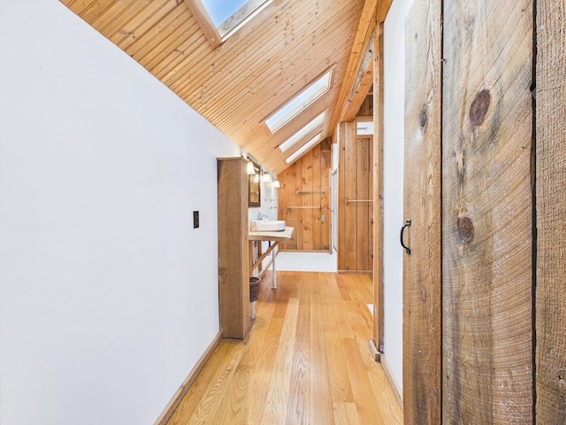 hallway featuring a skylight, lofted ceiling, light wood-type flooring, and wood ceiling