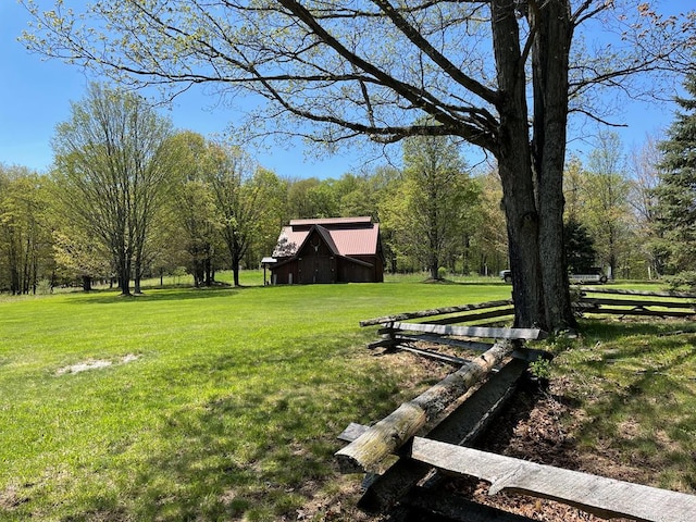 view of green lawn featuring a barn, a wooded view, and an outbuilding