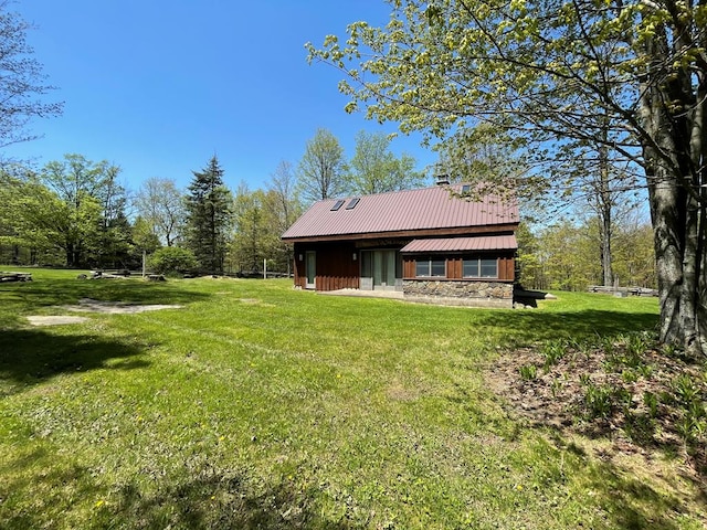 rear view of house with a lawn and metal roof