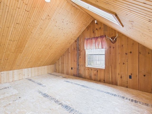 additional living space with lofted ceiling, wood walls, and a skylight