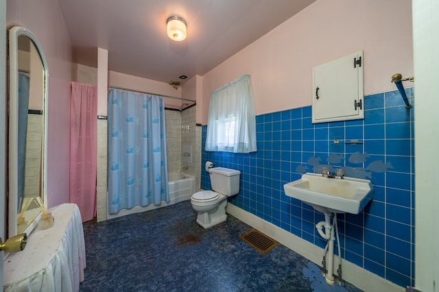 full bath featuring toilet, visible vents, tile walls, wainscoting, and shower / bath combo