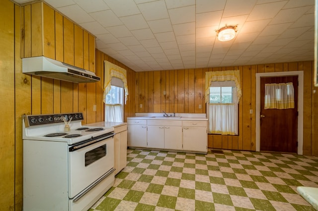 kitchen with under cabinet range hood, electric range, white cabinetry, light countertops, and light floors