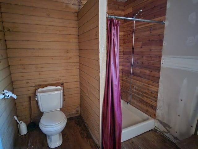 bathroom with wooden walls, toilet, hardwood / wood-style floors, and walk in shower