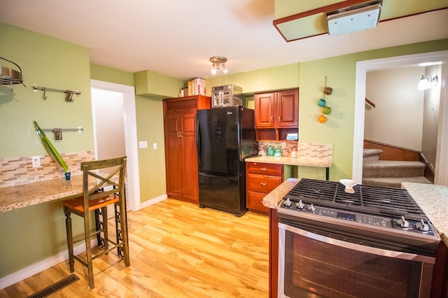 818 W Water St, Elmira, NY 14905 - kitchen featuring freestanding refrigerator, stainless steel gas range oven, light wood-style floors, tasteful backsplash, and brown cabinetry
