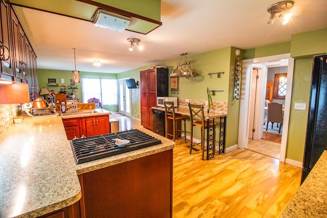 818 W Water St, Elmira, NY 14905 - kitchen with cooktop, light countertops, light wood-type flooring, a peninsula, and hanging light fixtures