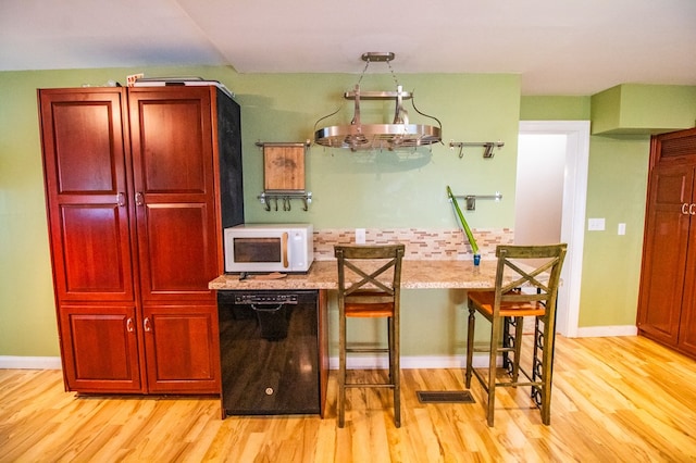818 W Water St, Elmira, NY 14905 - kitchen with dishwasher, white microwave, light wood-type flooring, and reddish brown cabinets