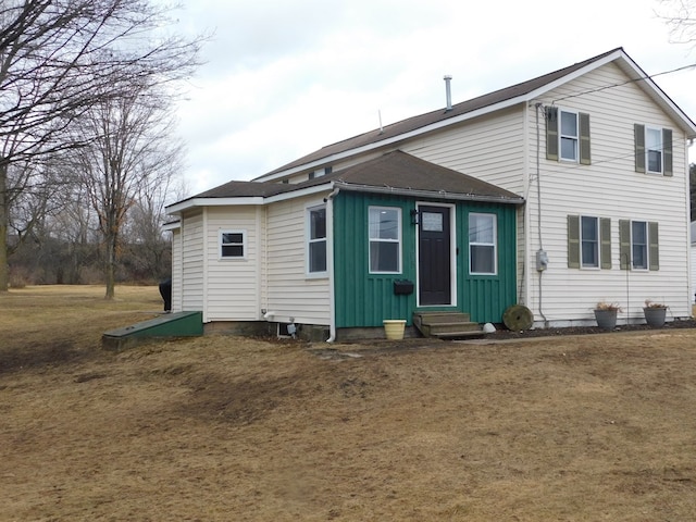 back of house featuring entry steps, a lawn, and board and batten siding